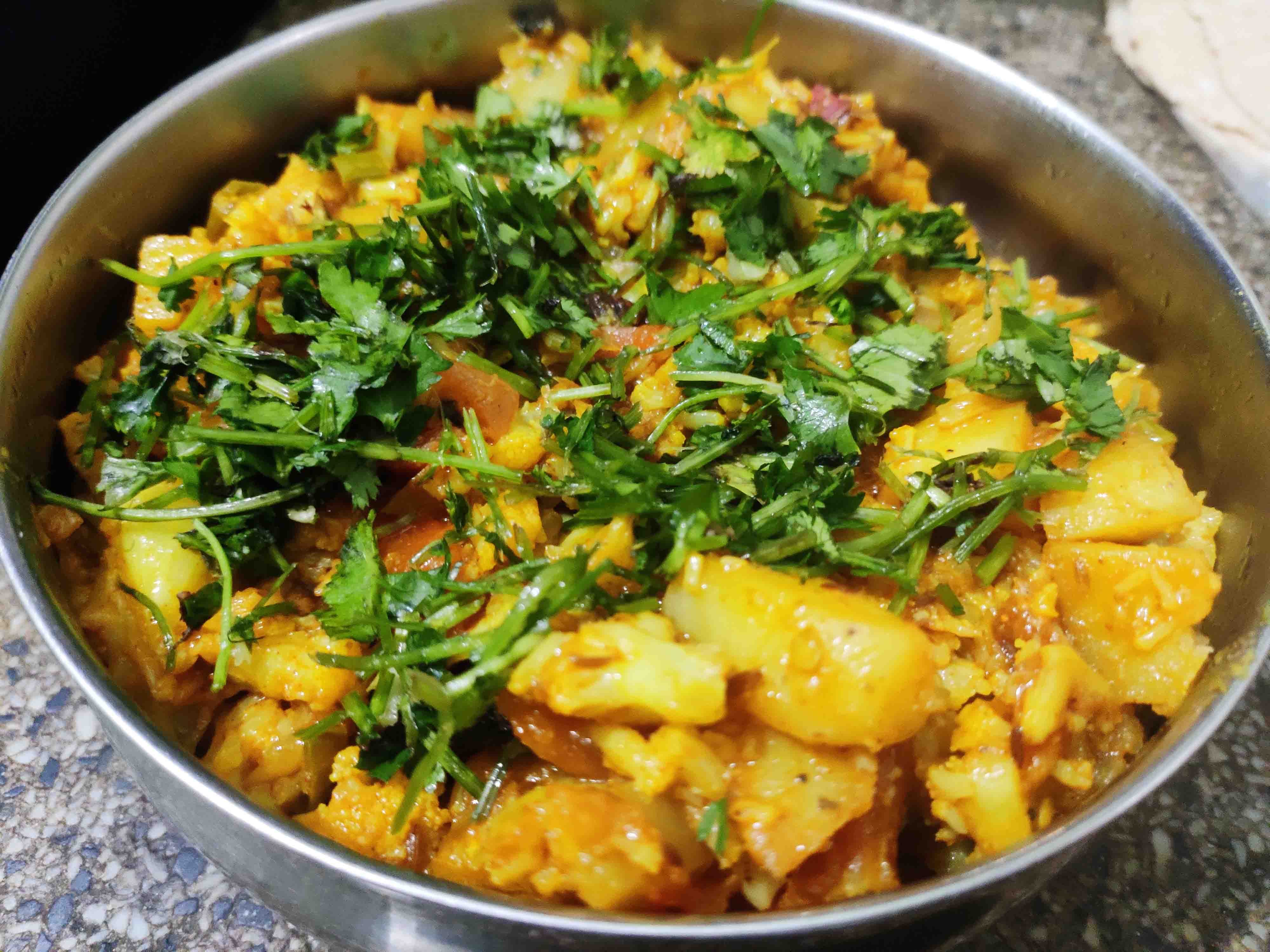 Potato and cauliflower tempered with cumin seeds stir-fried with onion and tomato sauce
